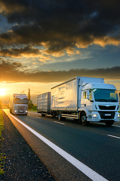 Overtaking trucks on an asphalt road in a rural landscape at sunset